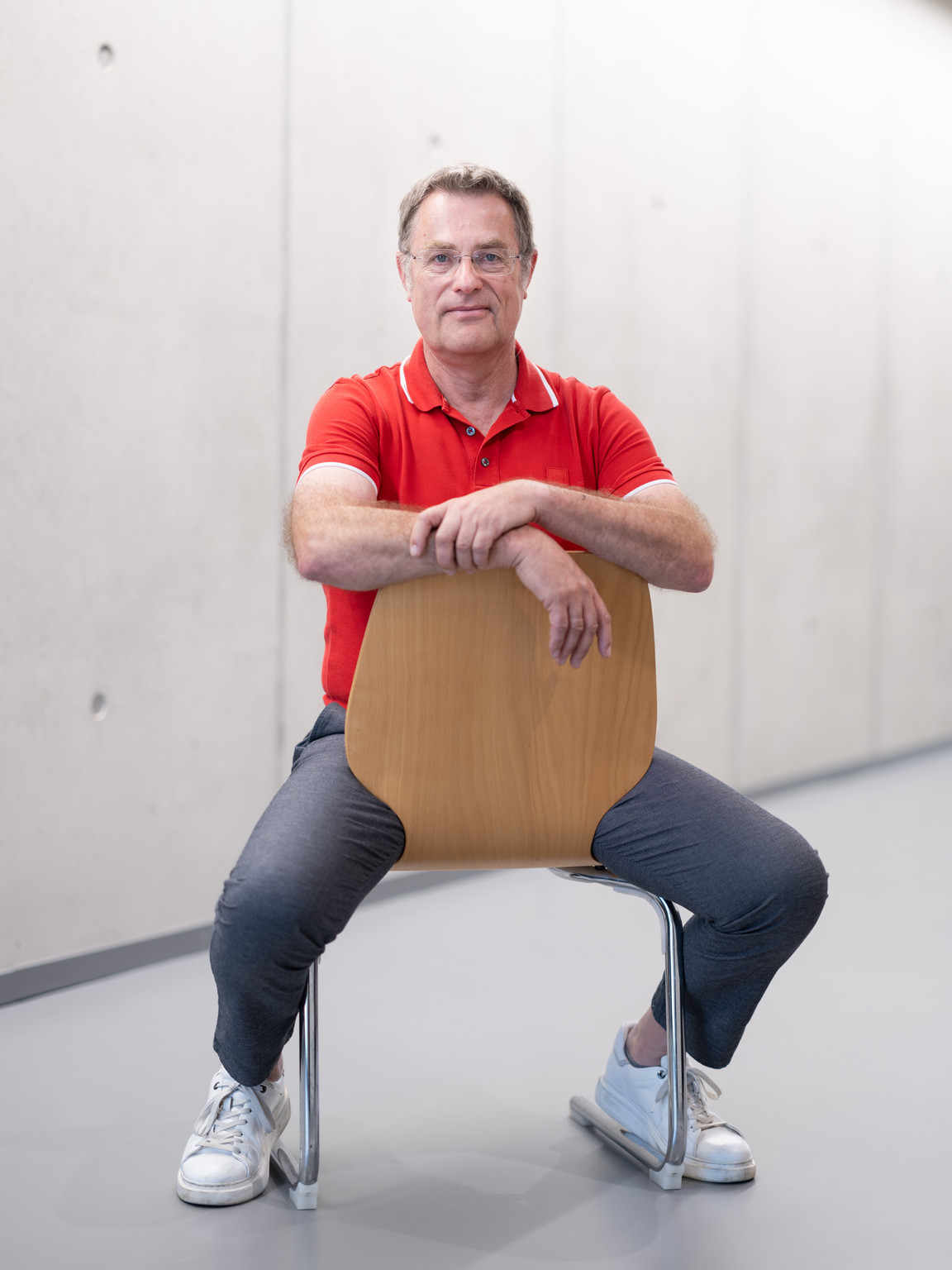 Prof. Matthias Upmann sitzt auf einem Stuhl in einem Hochschulgebäude